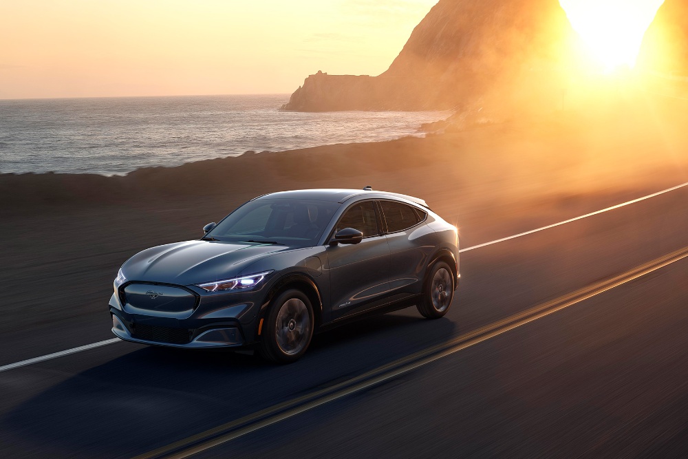Ford Mach-E electric, condus pe un drum de coastă, la asfințit.