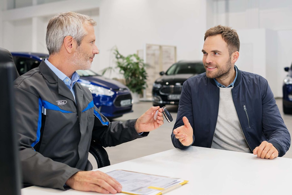 Two men sitting across from each other at a dealership