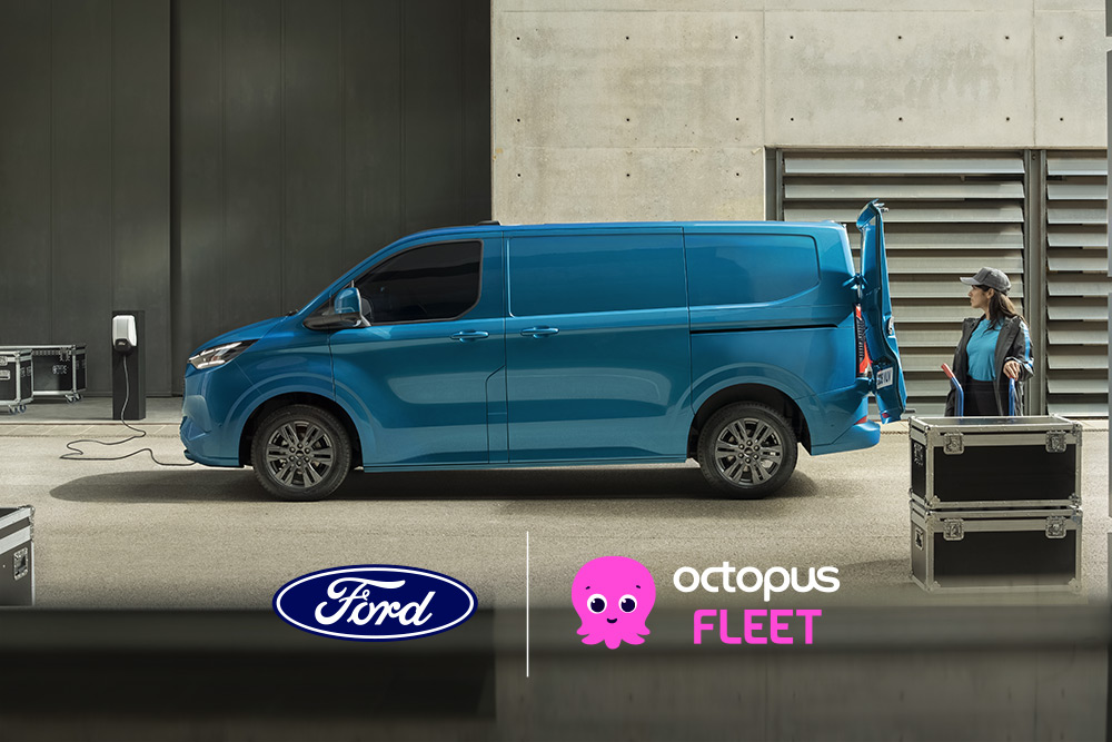 Vedere laterală a unui Ford E-Transit Custom albastru, parcat cu ușa din spate deschisă și o persoană stând în apropiere.