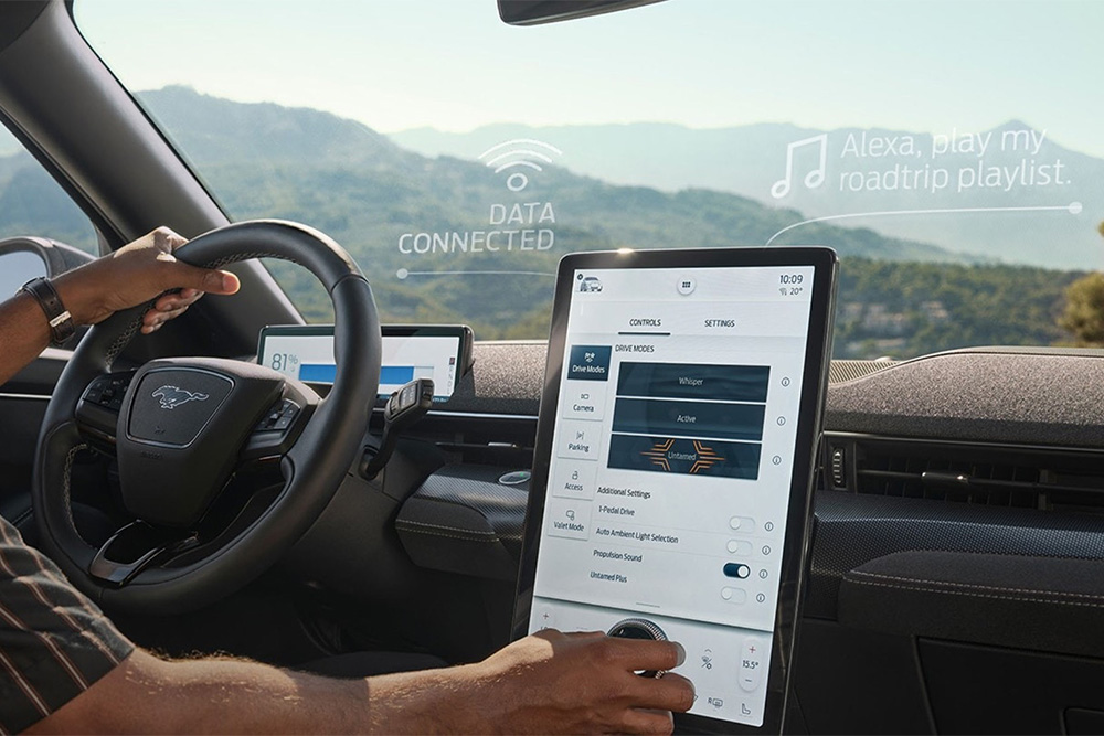 Prim-plan cu șoferul unui Ford Mustang Mach-E care interacționează cu ecranul tactil de 15,5" SYNC 4 ce afișează Apple CarPlay. 