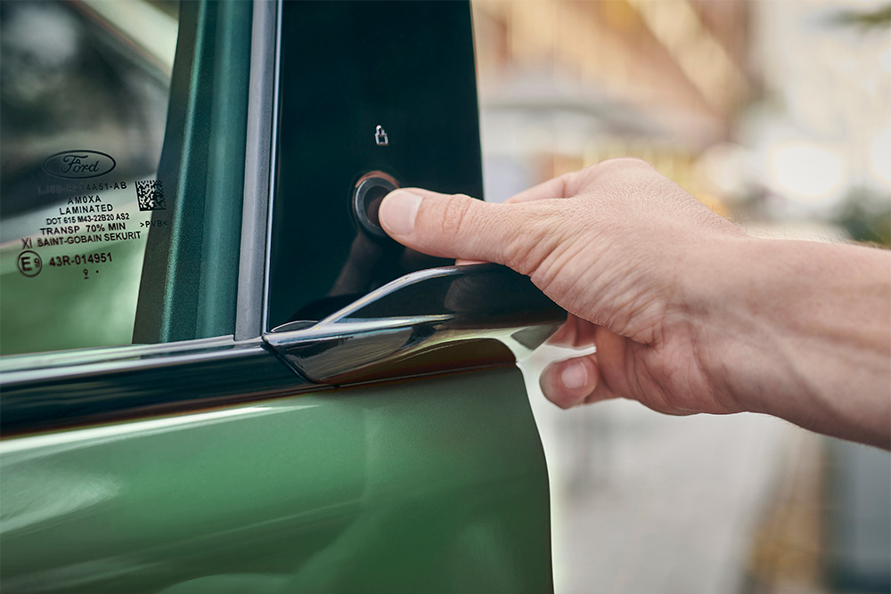 Prim-plan cu acționarea sistemului E-Latch prin apăsarea unui buton pe ușa unui Ford Mustang Mach-E verde.
