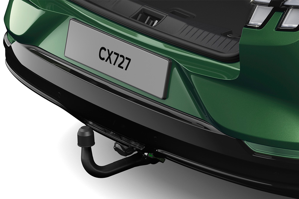 Prim-plan cu cârligul de remorcare electric al unui vehicul Ford Mustang Mach-E verde, fotografiat în studio pe un fundal alb.