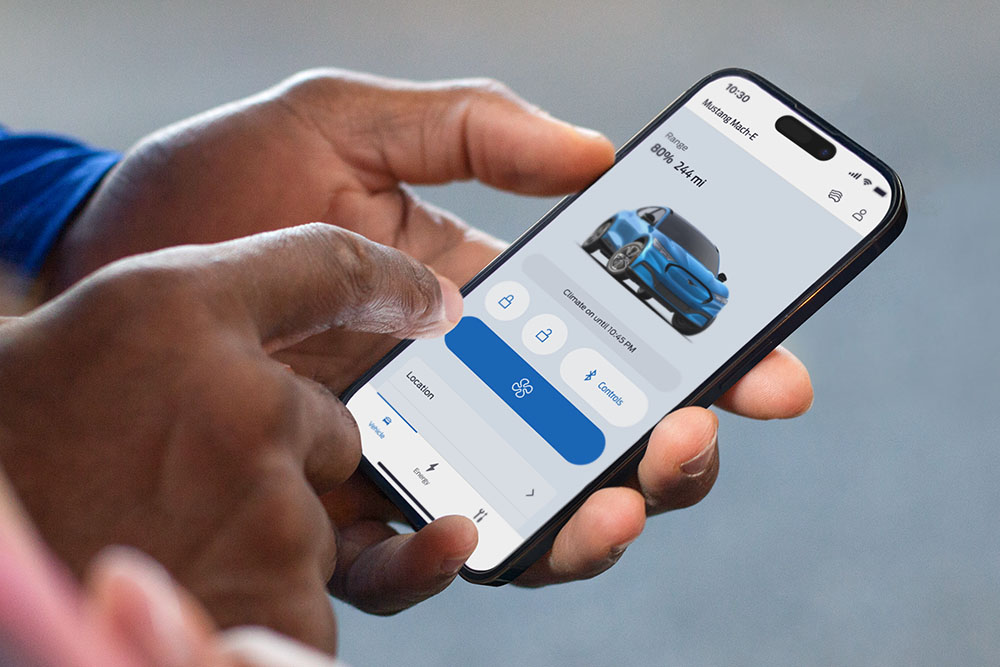 Prim-plan cu un iPhone care prezintă Ford app, cu o imagine a unui Ford Mustang Mach-E și mai multe butoane ale aplicației.