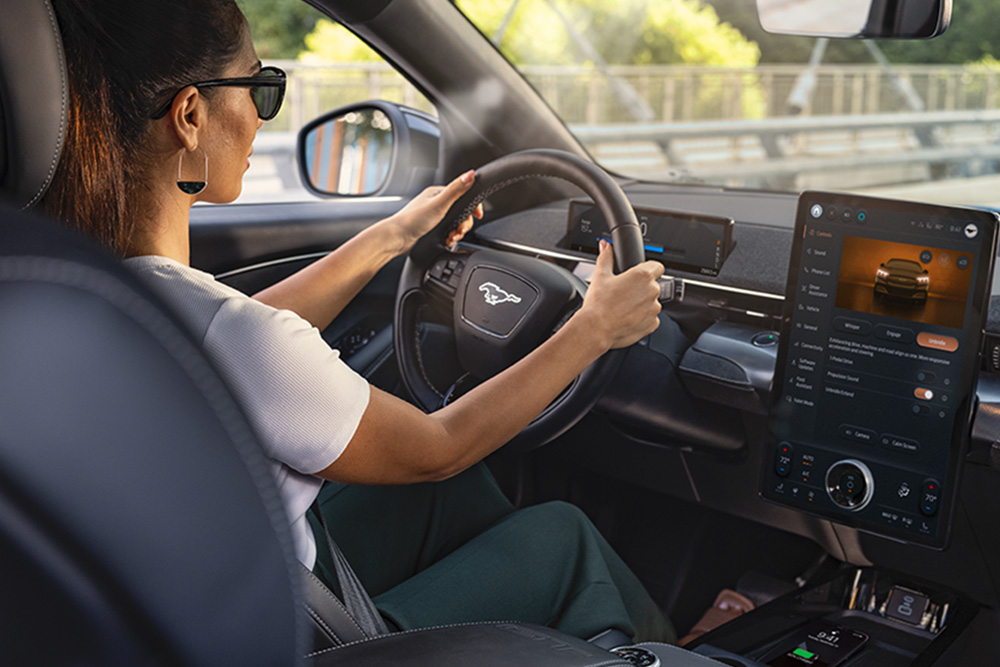 Interiorul modelului Ford Mustang Mach-E pe timp de noapte, care prezintă ecranul tactil SYNC 4 de 15,5" și iluminarea ambientală cu LED-uri setată pe culoarea portocaliu