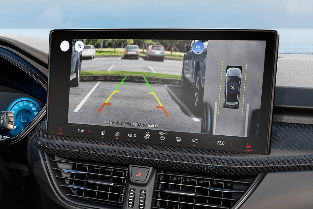 Vedere de aproape a interiorului unui  Ford Kuga, cu accent pe imaginea camerelor 360° pe ecranul vehiculului.