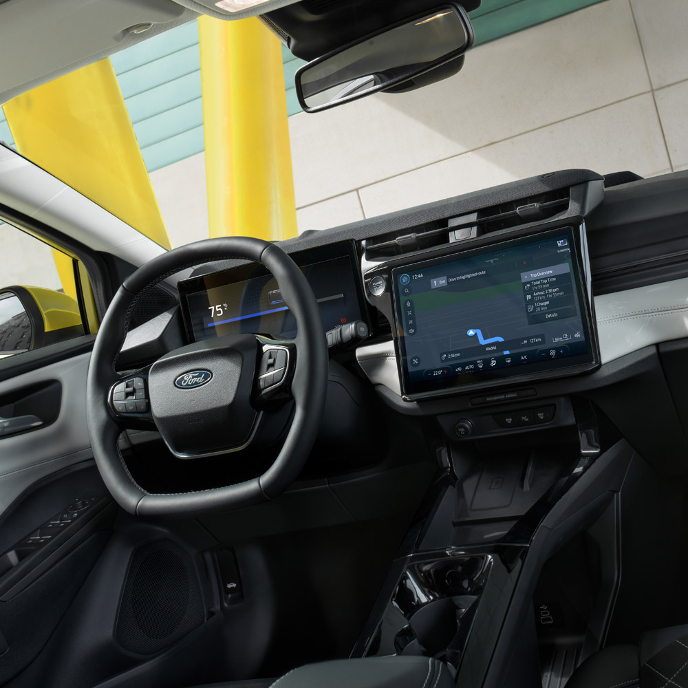 Vedere din interior a unui vehicul Ford Puma, cu prim-plan pe volan și pe ecranul tactil.
