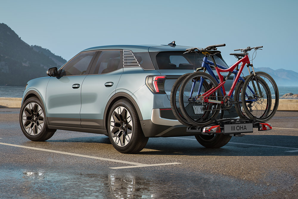 Ford Explorer albastru deschis, condus pe drum neasfaltat, dotat cu bare transversale și două biciclete montate pe suporți pe plafon.