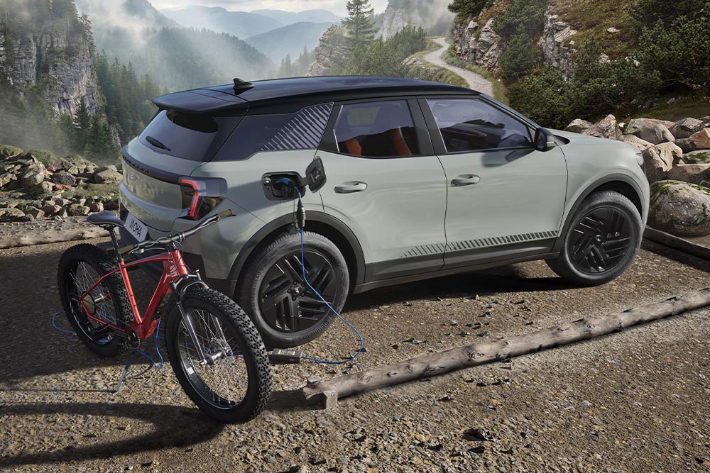 O bicicletă electrică ce se încarcă de la un Ford Explorer®, într-un peisaj montan pe fundal.
