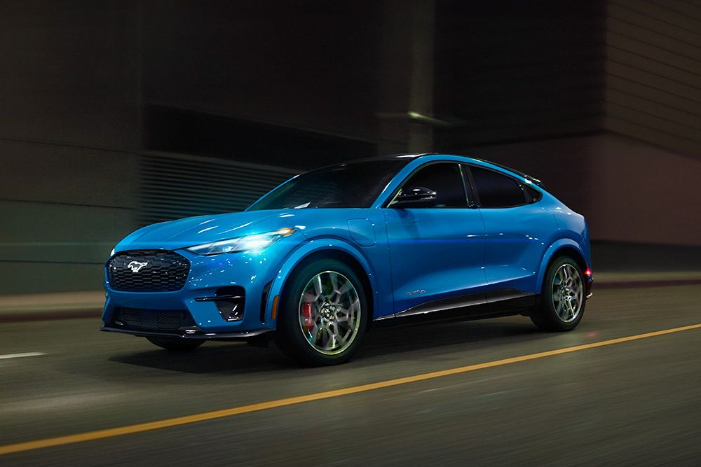 O mașină sport electrică Ford Mustang Mach-E GT albastră, care se deplasează pe un drum deschis.