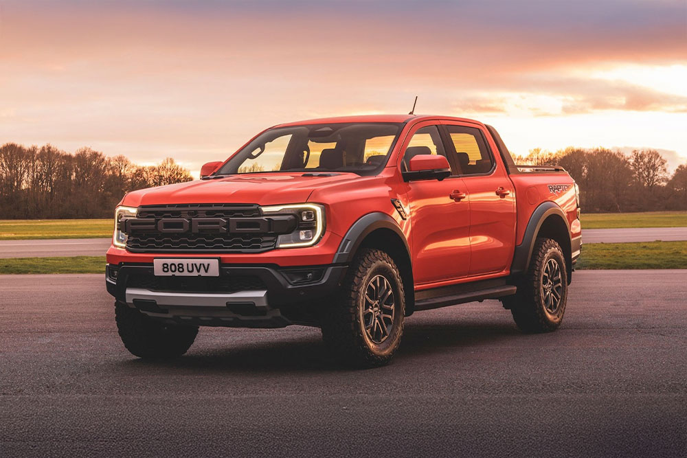 O camionetă portocalie Ford Ranger Raptor parcată într-un peisaj pitoresc.