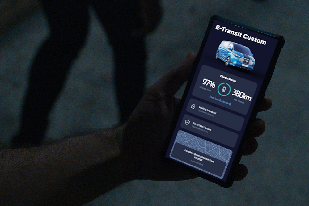 Smartphone care afișează un E-Transit Custom în aplicația Ford, afișând starea de încărcare a vehiculului și locația.