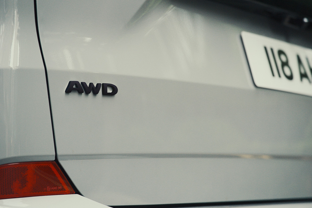 Partea din spate a unui Tourneo Custom de culoare gri argintiu, cu emblema "AWD"