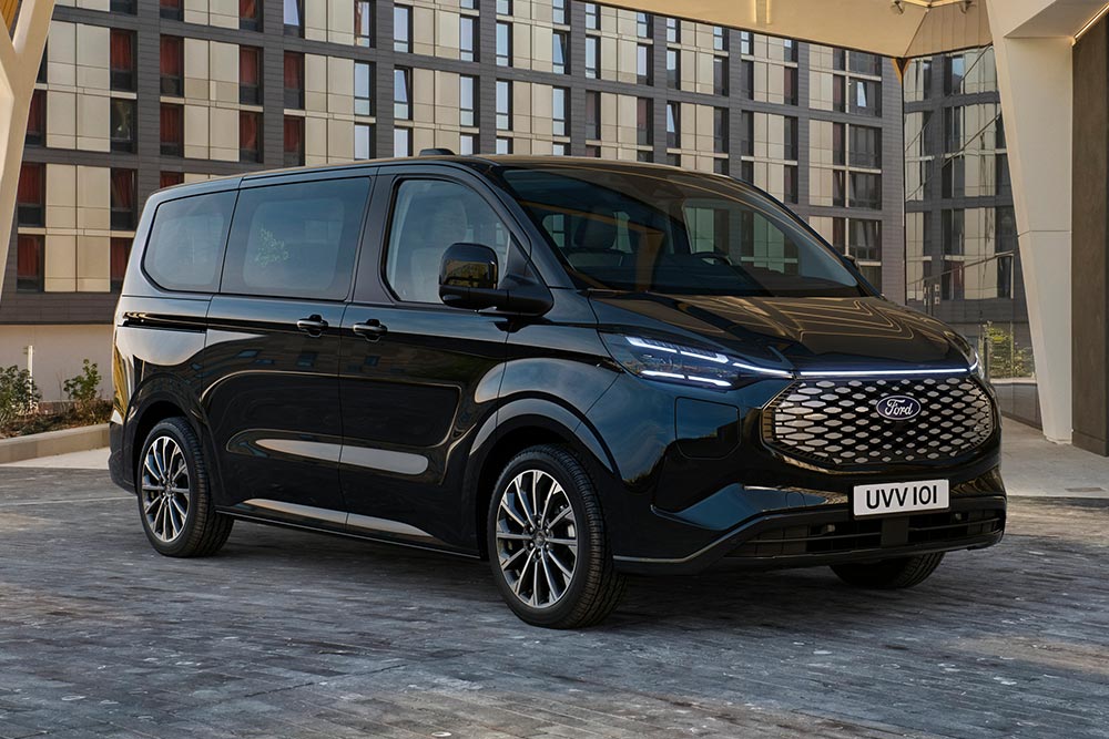 Un Ford E-Tourneo Custom negru este parcat în fața unei clădiri moderne.